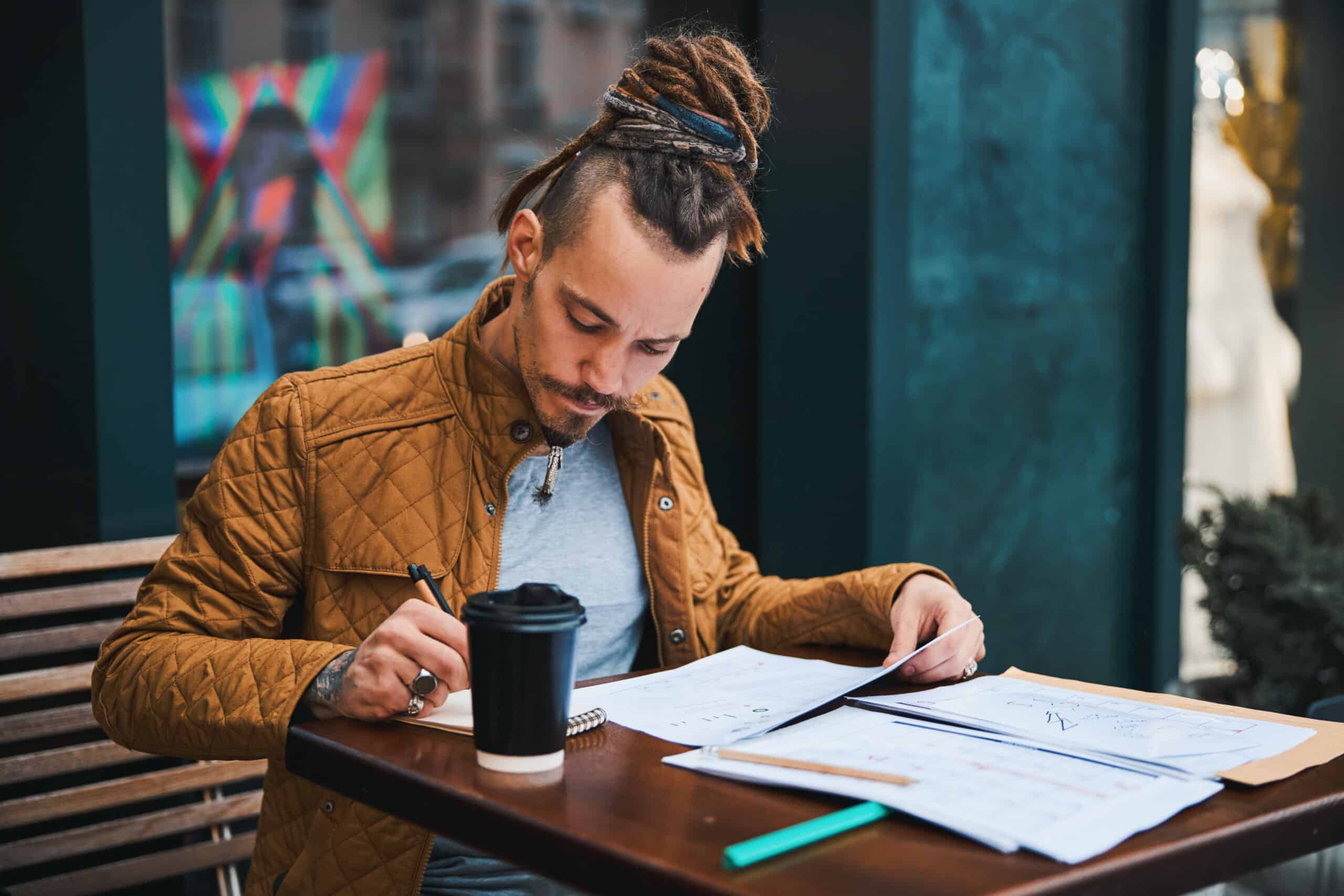 Creative young man studying in street cafe