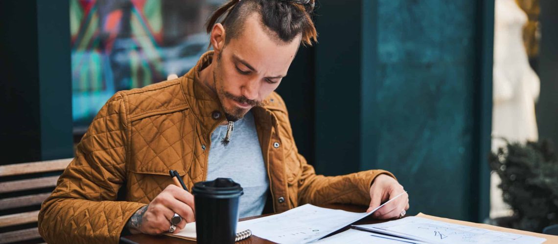 Creative young man studying in street cafe